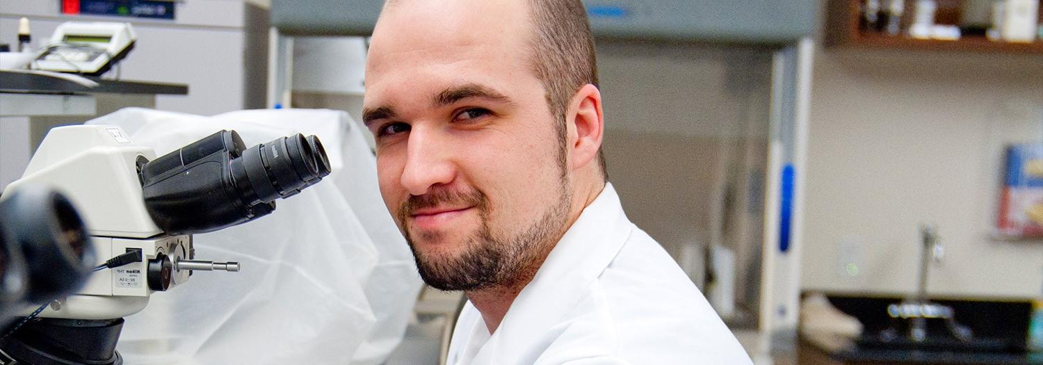 man sitting in front of a microscope