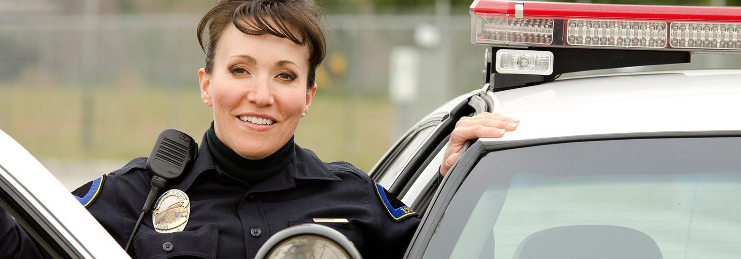 Smiling police officer standing at door of her car