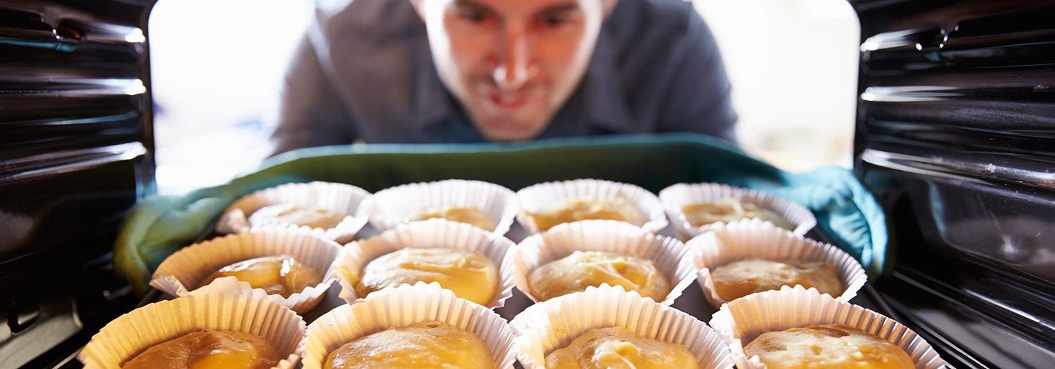 person taking baked goods out of an oven